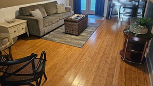 A living room with a grey sofa, a coffee table, a side table, and a wooden floor. - The Lofts of Downtown (540 N 2nd St, #105) (Clarksville)