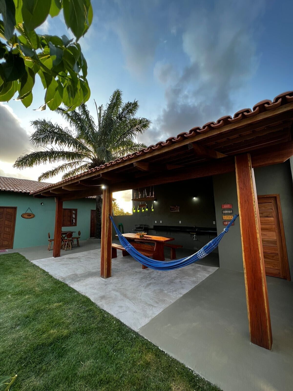 A patio area with a hammock, a dining table, and a kitchen visible through an open door.