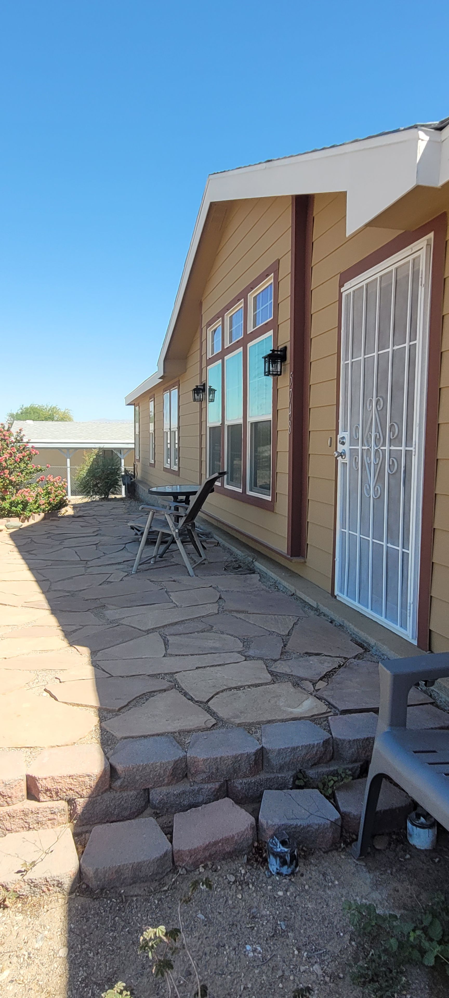 A residential building with a patio area, stone flooring, and a small table with chairs.