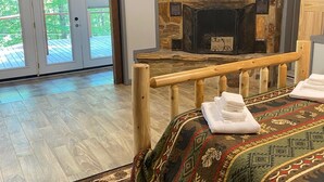 A hotel room with a bed, a fireplace, a wooden bench, and a view of the outdoors.