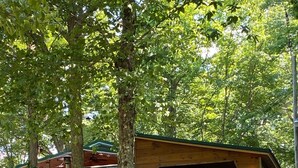 A rustic wooden building with a sloped roof, a covered entrance, and a satellite dish on the side.