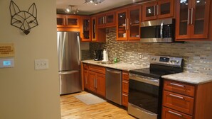 A modern kitchen with wooden cabinets, stainless steel appliances, and a tiled backsplash.