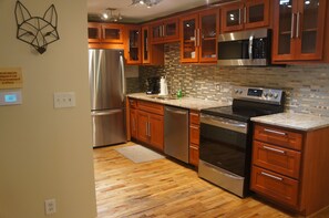 Kitchen features stainless steel appliances, a large island, and a mosaic tile backsplash.