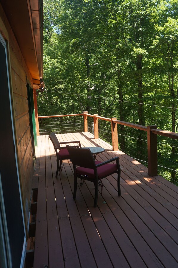 Relax on the deck with a view of the lush forest, surrounded by a comfortable seating area.