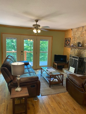 Relax in this inviting living space with a comfortable sofa, glass coffee table, and stone fireplace.