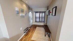 A hallway with a wooden floor, a bench, a rug, and wall decorations. - Beautiful Bungalow nestled in Nelsonville near Hocking Hills (Nelsonville)