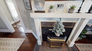 A fireplace with a decorative tree, a framed sign, and potted plants.