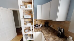 A kitchen with white cabinets, a granite countertop, a coffee maker, and a blender.