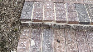 Un chemin pavé, orné de motifs complexes en mosaïque, mène à une structure en béton.