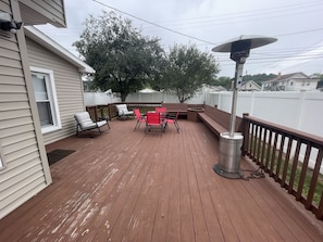 Eine Holzterrasse mit Gartenmöbeln, darunter Stühle und ein Tisch, sowie ein Metallheizkörper.