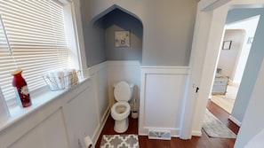 Ein kleines Badezimmer mit Toilette, Handtuchhalter und einem Fenster mit Jalousien.