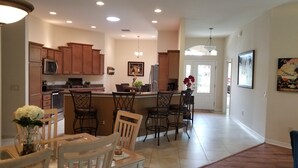 Una cocina amplia con armarios de madera, una isla central con taburetes de bar y un comedor con mesa y sillas.