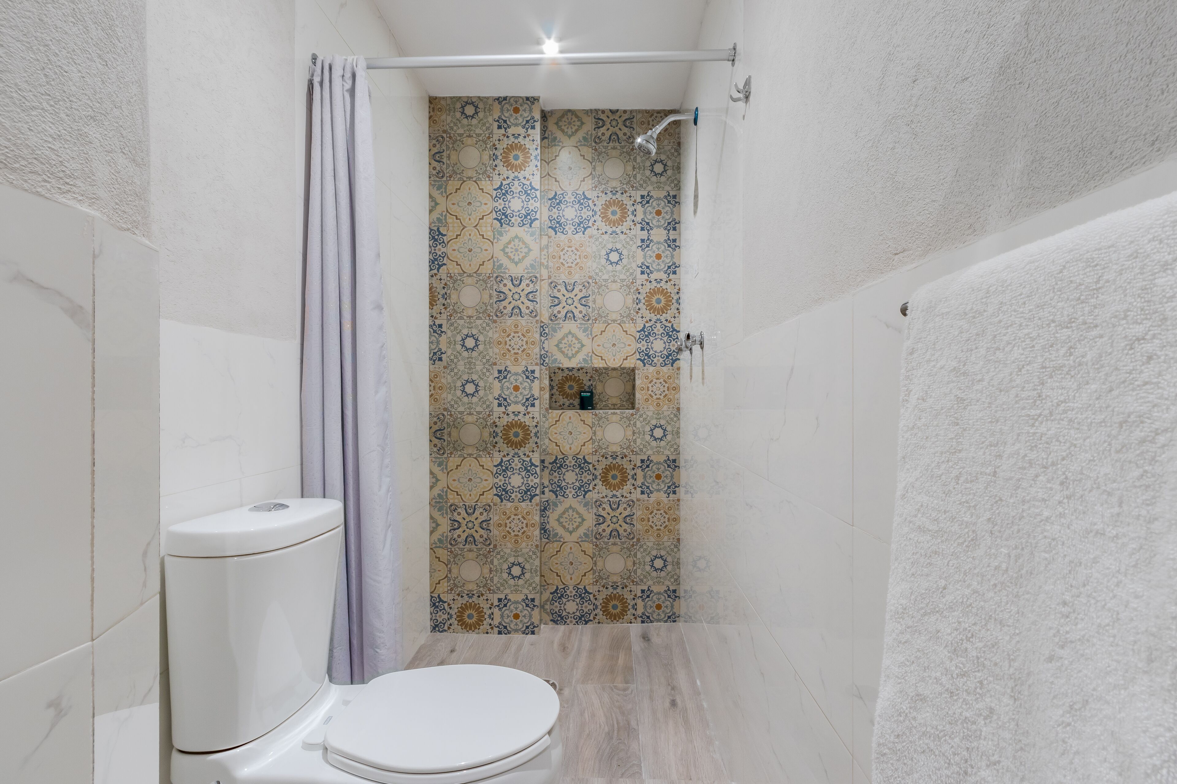 Une salle de bain avec des toilettes, une douche et des carreaux décorés.