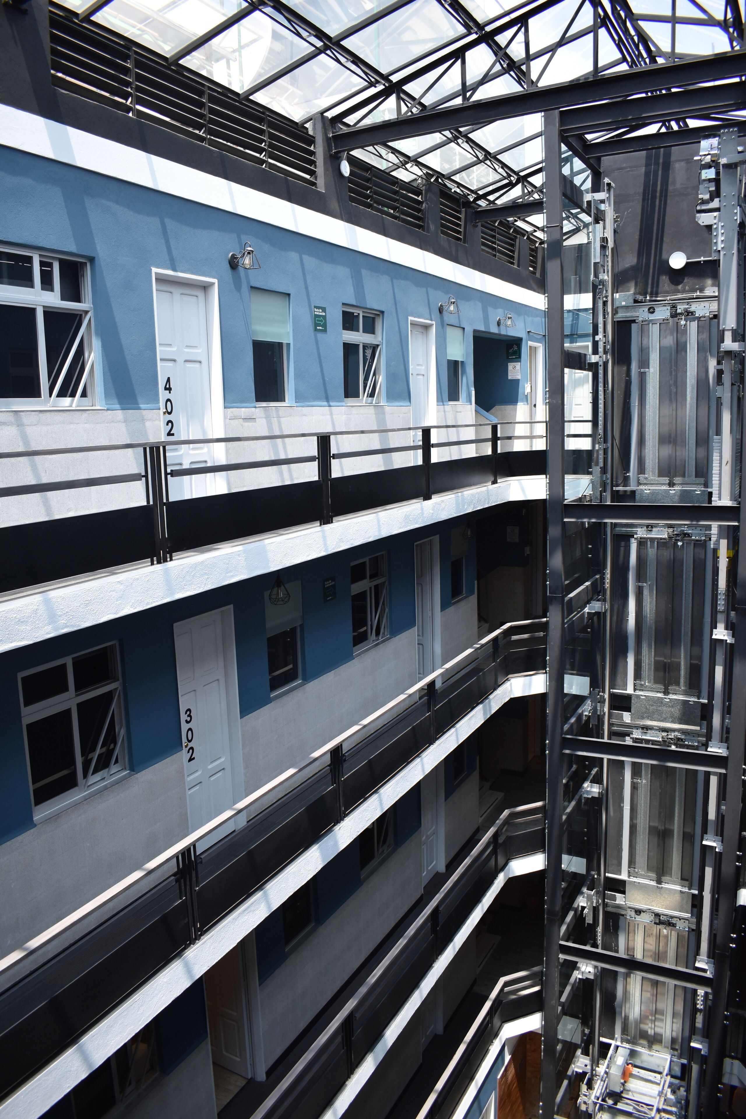 Een hotel met meerdere verdiepingen en een modern design, met balkons en een glazen lift.