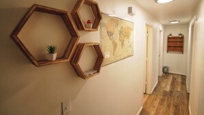 A hallway with hexagonal wooden frames on the wall, a world map, and a small plant in one frame. - Wooded river retreat near Mt. Bachelor and Bend (Bend)