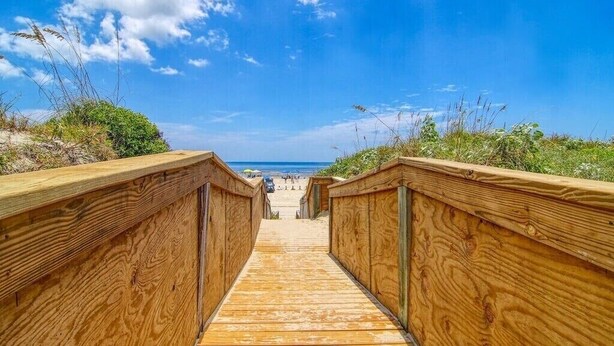 A wooden boardwalk leading to a beach with a clear blue sky. - Sea the View Casita-ADA access + heated community pool.hot tub,beach boardwalk (Port Aransas)