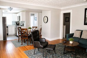 Una sala de estar moderna con un sofá verde, una mesa de centro y un comedor con sillas de madera y una mesita.