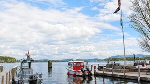 A dock with boats, a flag, and a view of the water and mountains.