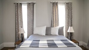 A bedroom with a large bed, two bedside tables, and curtains.