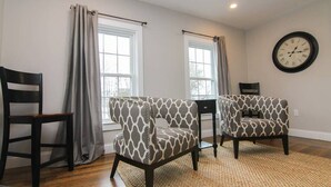 A room with two patterned armchairs, a small table, and a wall clock. - Beautiful Lake Winnipesaukee Getaway in Wolfeboro (Wolfeboro)