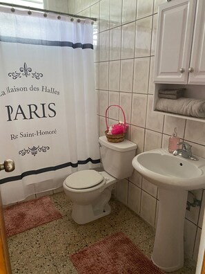 A bathroom with a toilet, sink, and a shower curtain with text. - Lomita Linda just minutes from San Juan and Central to all Puerto Rico  (Caguas)