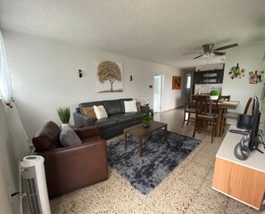 A living room with a sofa, coffee table, and a dining area with chairs and a table. - Lomita Linda just minutes from San Juan and Central to all Puerto Rico  (Caguas)