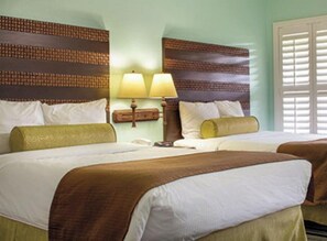 Two single beds with matching headboards and footboards, a nightstand with a lamp, and a window with blinds.
