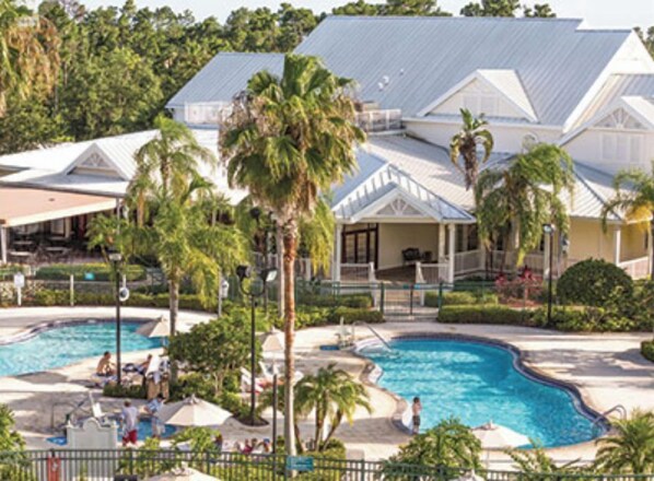 Relax by the resort's inviting pool surrounded by lush greenery and palm trees.