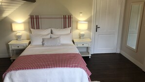 Un dormitorio con una cama, dos mesitas de noche con lámparas, una puerta y una ventana.