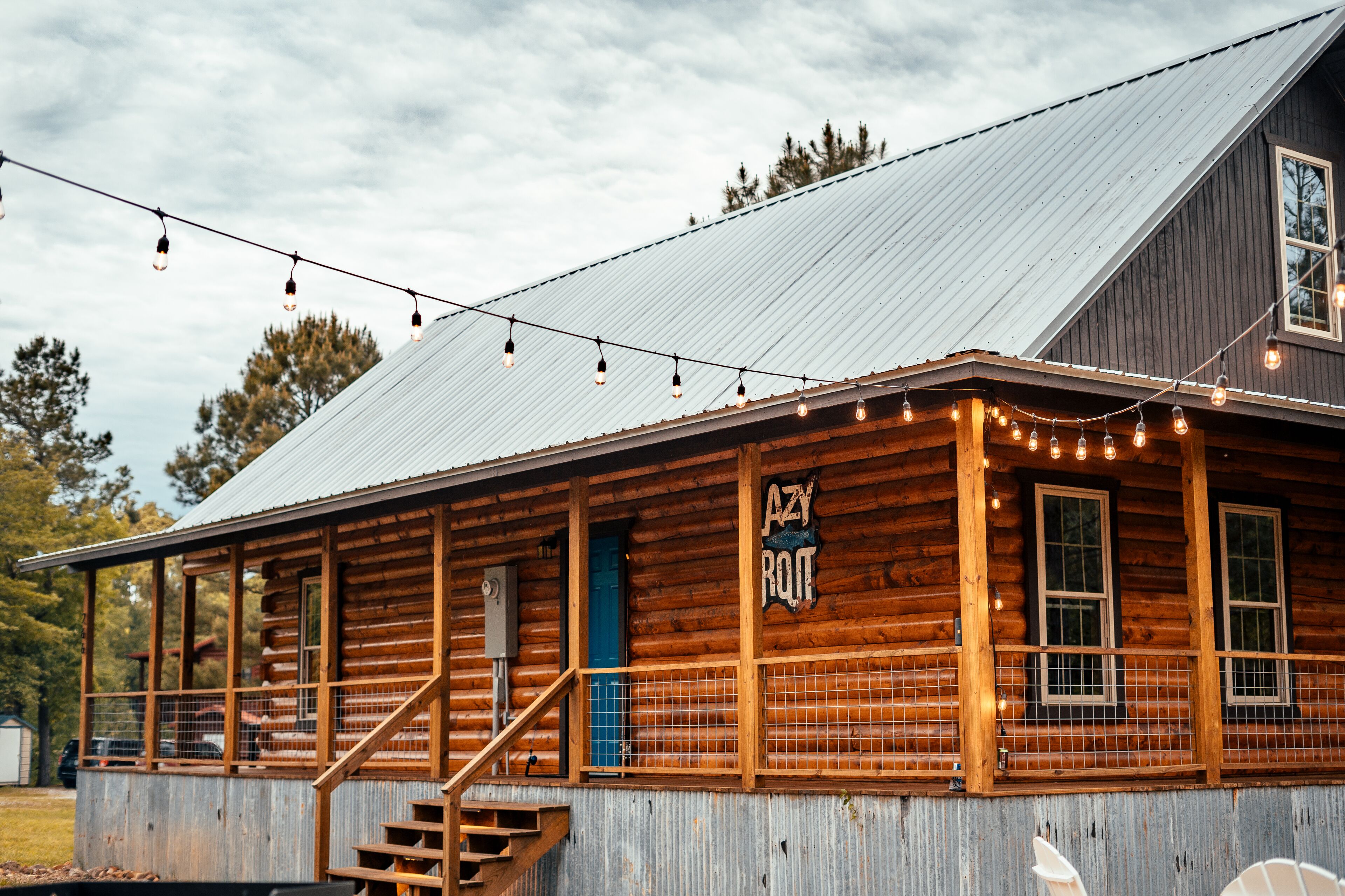 A rustic log cabin with a metal roof, wooden exterior, and a sign reading "AZY ROQUE".