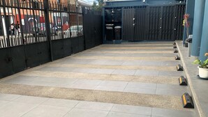Una terrassa al terrat amb sòl de rajola, una tanca de metall negre i una porta que dona a un edifici.