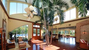 A spacious lobby with a high ceiling, large windows, and a central palm tree.