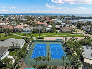 An aerial view of a residential area with two tennis courts surrounded by houses and palm trees. - The New GameHaus at Destin | Ultimate Game Room (Destin)