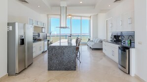 A modern kitchen with stainless steel appliances, a granite island, and a large window offering a view. - Luna Blanca 1201 by Kivoya (Puerto Peñasco)
