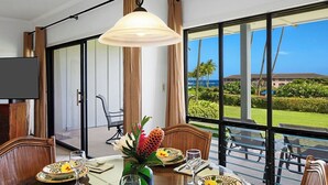 A dining area with a table set for four, a large window with a view of a golf course, and a television on the wall.