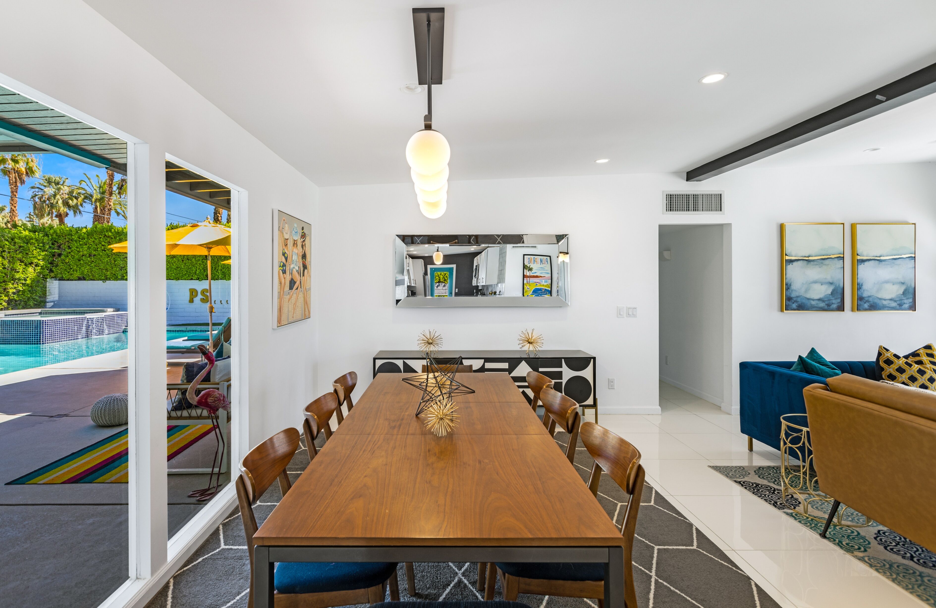 A modern dining area with a wooden table, chairs, and a hanging light fixture.