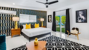 Une chambre à coucher moderne, équipée d’un lit, de tables de chevet, d’un ventilateur de plafond et offrant une vue sur l’extérieur.