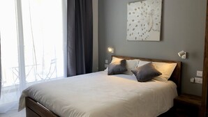 Een slaapkamer met een bed, twee bedlampen, een raam met gordijnen en een wanddecoratie.