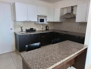 A kitchen with white cabinets, a microwave, a stove, and a granite countertop.