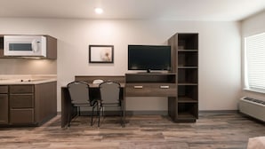 A modern kitchen with a microwave, a dining area with two chairs, a TV on a wooden stand, and a built-in bookshelf. - Woodspring Suites Philadelphia Northeast (Philadelphia)