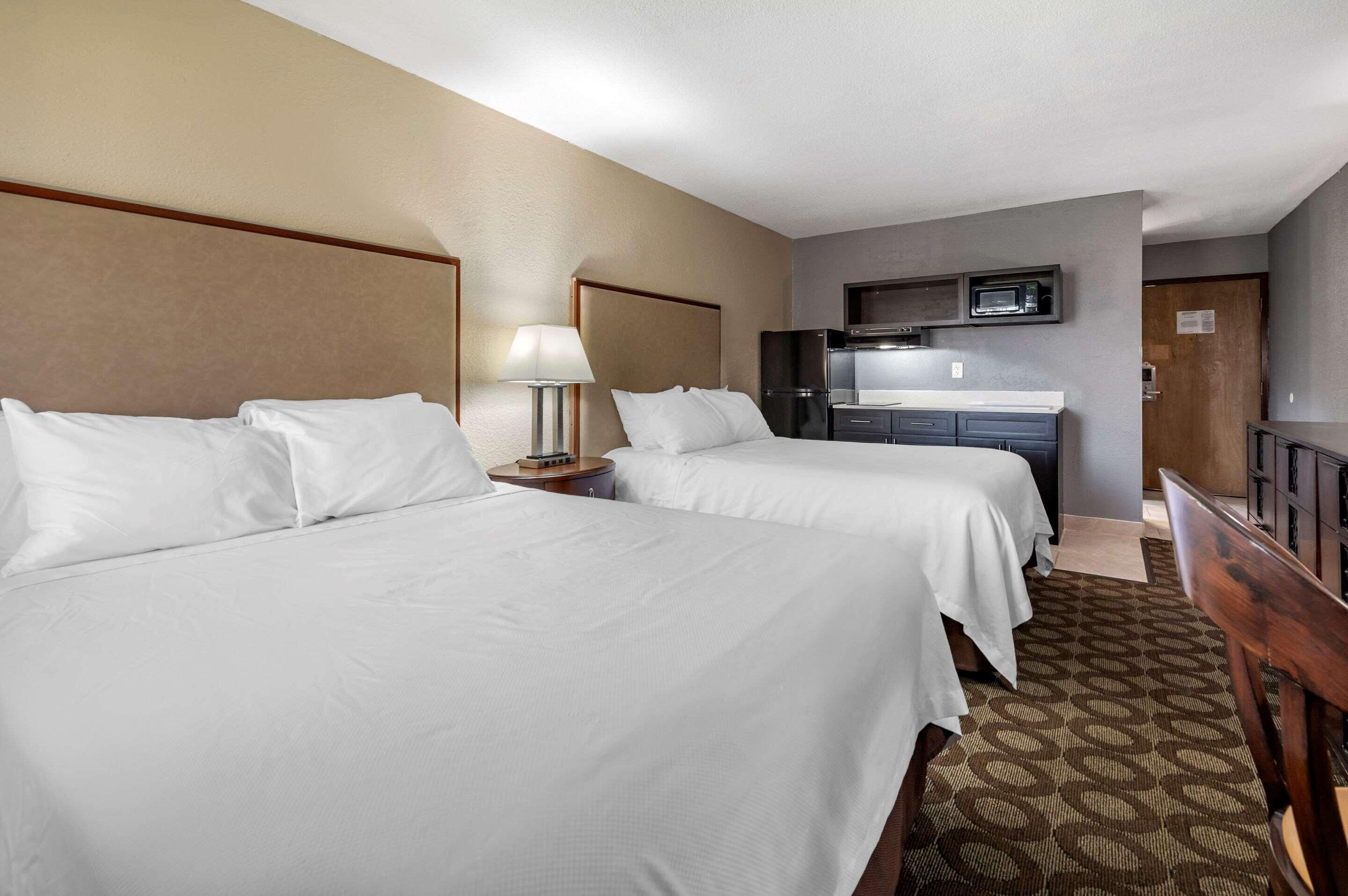 A hotel room with two beds, a desk, a microwave, and a TV.