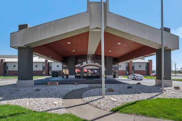 A modern building with a covered entrance, large pillars, and a gravel pathway leading to the entrance. - Suburban Studios Lafayette (Lafayette)