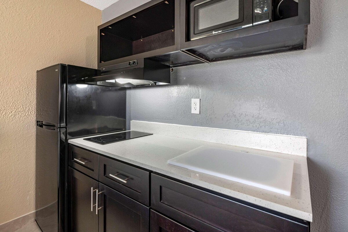 A compact kitchen with a black refrigerator, a microwave, a built-in oven, and a white countertop.