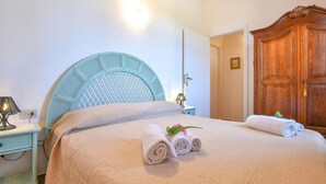 Een netjes opgemaakt bed met opgerolde handdoeken en een decoratief hoofdeinde.