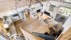 Une cuisine moderne avec un coin repas, un plancher en bois et un escalier menant à une chambre à coucher située en mezzanine.