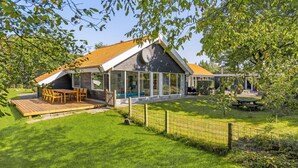 Une maison moderne dotée d’une grande terrasse, d’une piscine et d’un jardin clôturé.