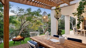 Un espace extérieur aménagé pour les repas, avec une table en bois, des chaises et un foyer.