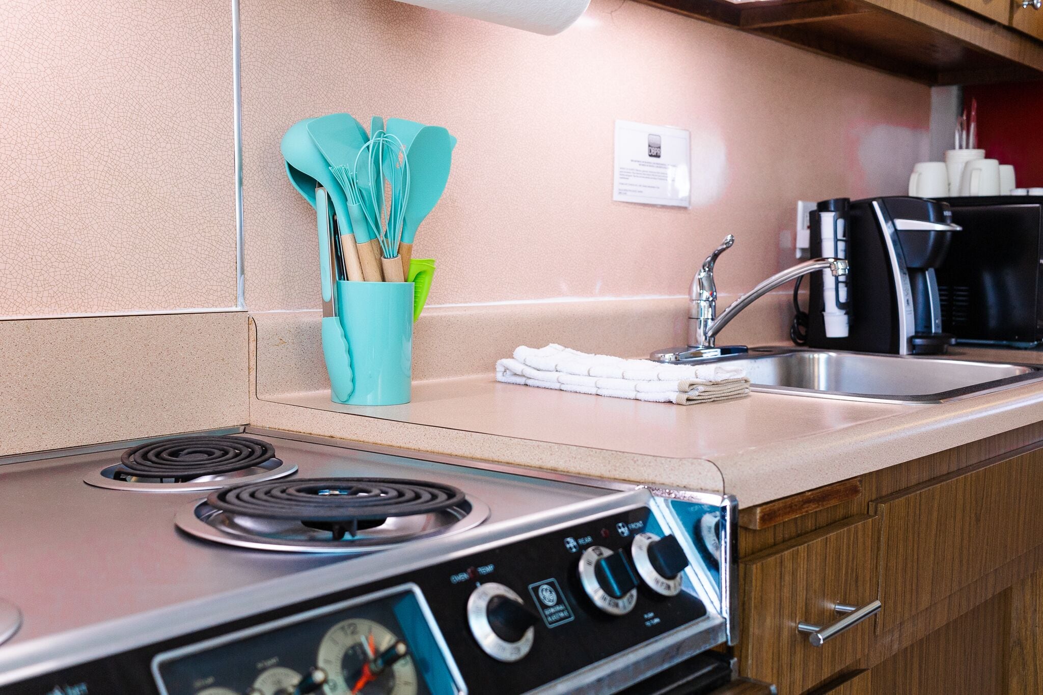 Una kitchenette equipada con estufa, lavamanos y cafetera.