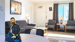 Een moderne woonkamer met een bank, twee fauteuils, een salontafel en een decoratief beeldhouwwerk.