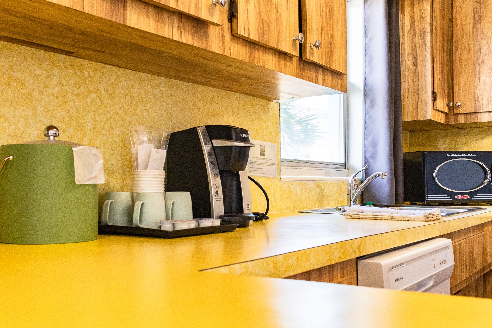 A kitchen with wooden cabinets, a coffee maker, and a dishwasher.